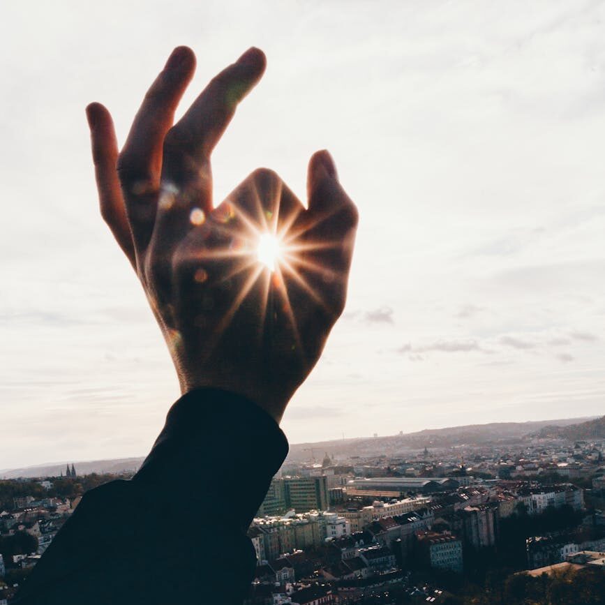 force perspective photography of hand and sun